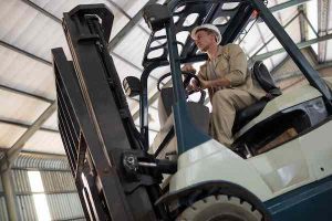 Worker driving forklift in oil factory